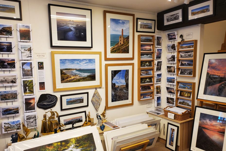 Photograph of Mick Blakey's display at Cscape Art, featuring framed photographs of Cornish landscapes and seascapes. On the left it a rack of greeting card featuring the photography.