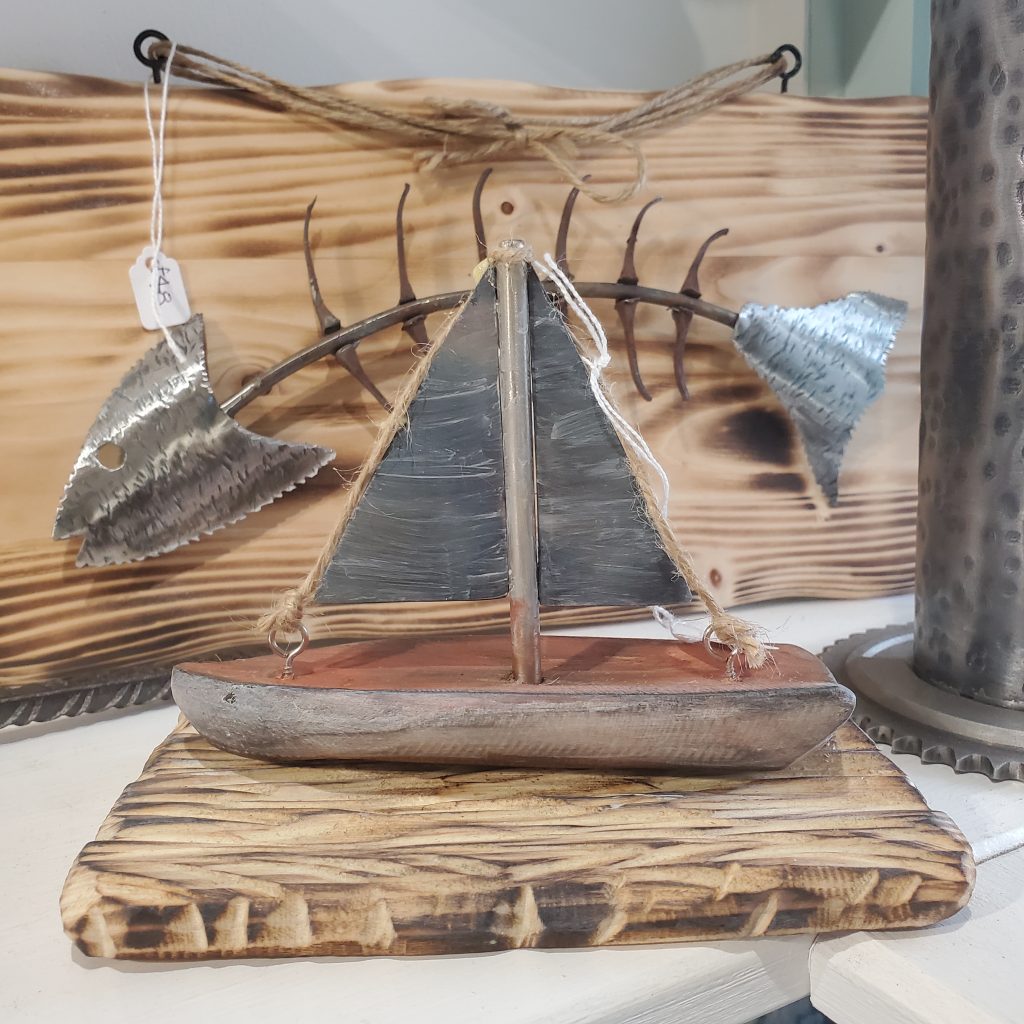 Photograph of Rusty Wave Metal Art's display featuring a metal boat mounted on a wooden base.