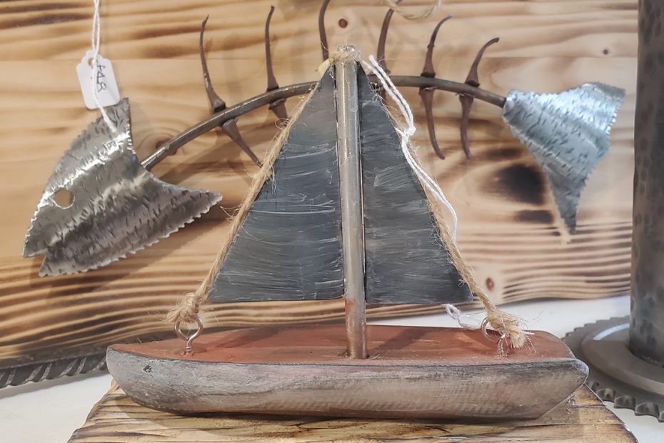 Photograph of Rusty Wave Metal Art's display featuring a metal boat mounted on a wooden base.